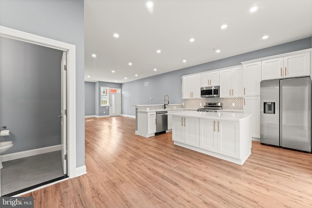 kitchen featuring white cabinetry, tasteful backsplash, light wood-type flooring, kitchen peninsula, and stainless steel appliances