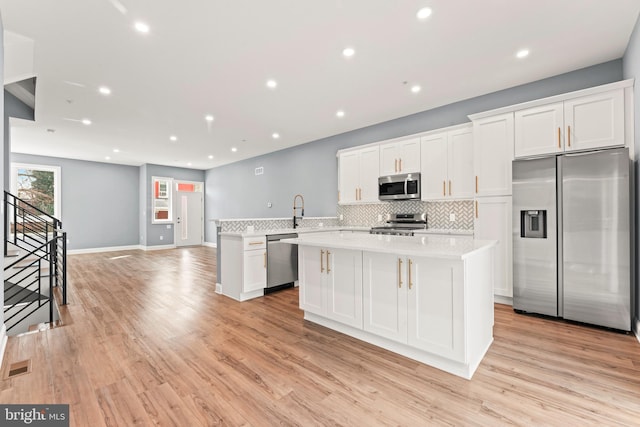 kitchen with backsplash, stainless steel appliances, kitchen peninsula, and white cabinets