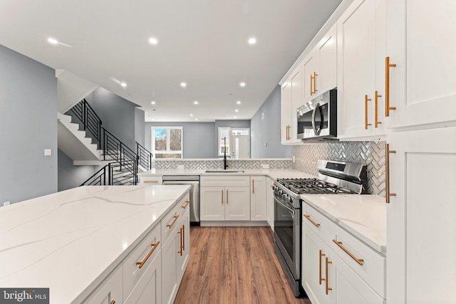 kitchen featuring sink, light stone counters, tasteful backsplash, appliances with stainless steel finishes, and white cabinets