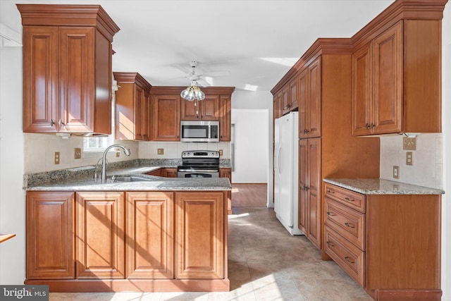 kitchen featuring light stone counters, sink, kitchen peninsula, and appliances with stainless steel finishes