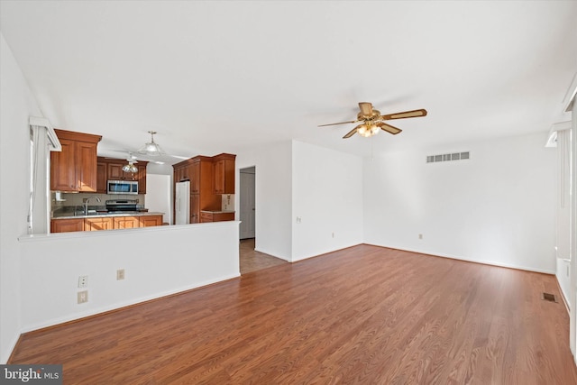 unfurnished living room with sink, hardwood / wood-style floors, and ceiling fan