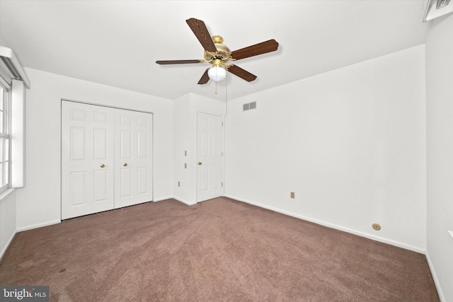 unfurnished bedroom featuring dark colored carpet, ceiling fan, and a closet