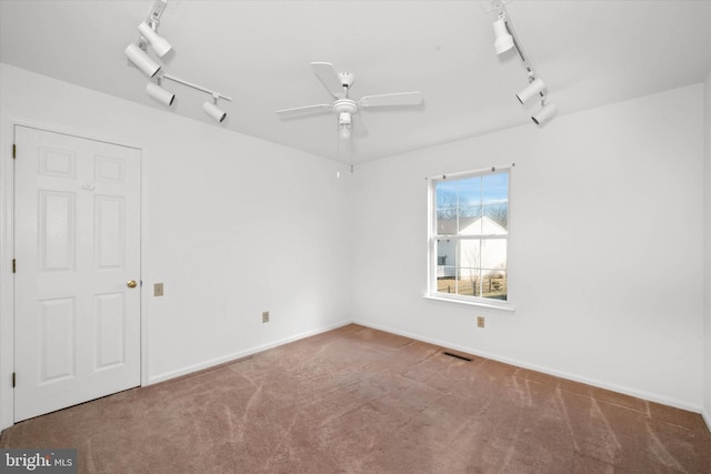 spare room featuring carpet floors, ceiling fan, and track lighting