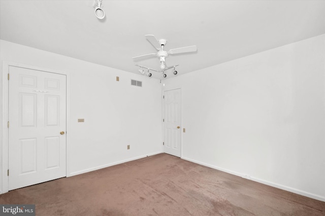 carpeted spare room featuring track lighting and ceiling fan