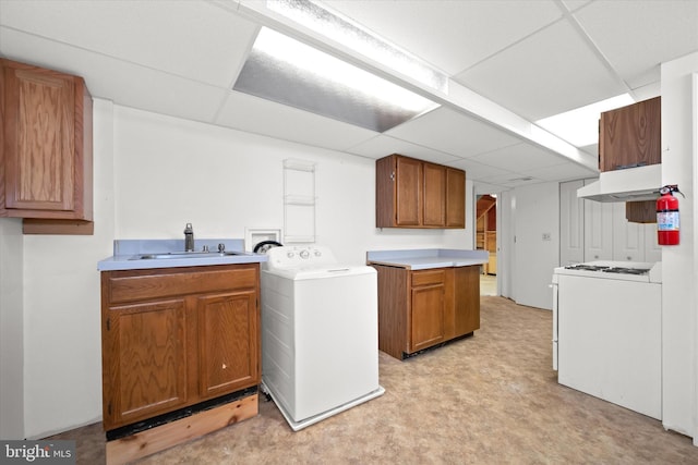 clothes washing area featuring sink, washing machine and dryer, and cabinets