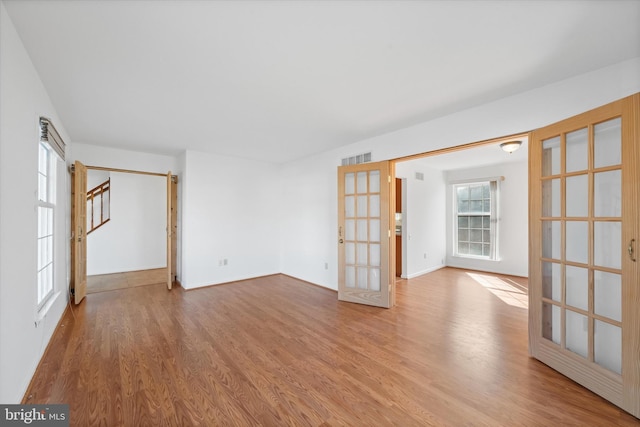 unfurnished room featuring french doors, a healthy amount of sunlight, and light wood-type flooring