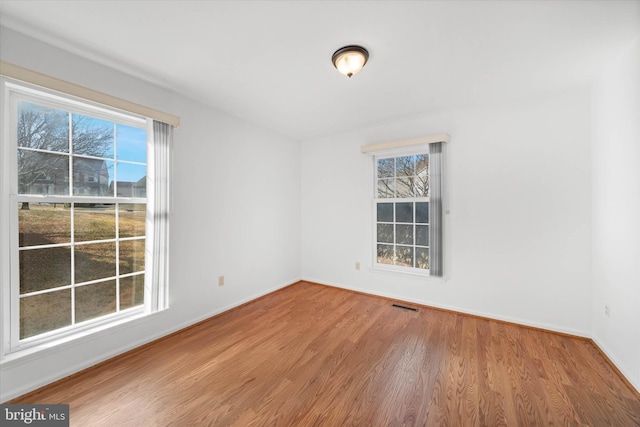 empty room with a healthy amount of sunlight and hardwood / wood-style floors