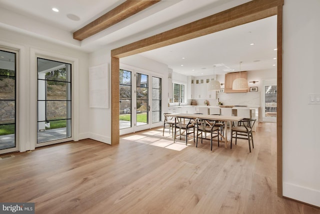 dining room featuring beamed ceiling and light wood-type flooring