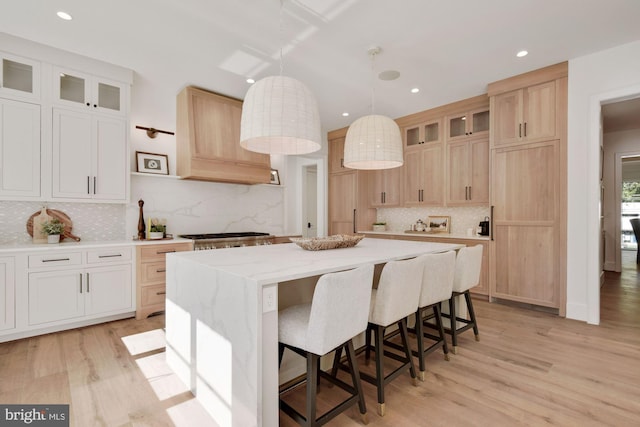 kitchen with pendant lighting, light hardwood / wood-style flooring, a center island, and white cabinets