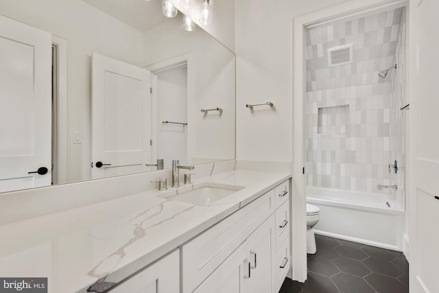 full bathroom with vanity, tiled shower / bath, tile patterned floors, and toilet