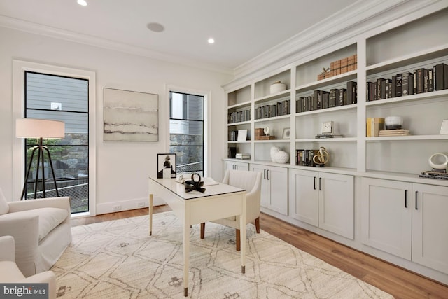 home office with crown molding and light hardwood / wood-style floors