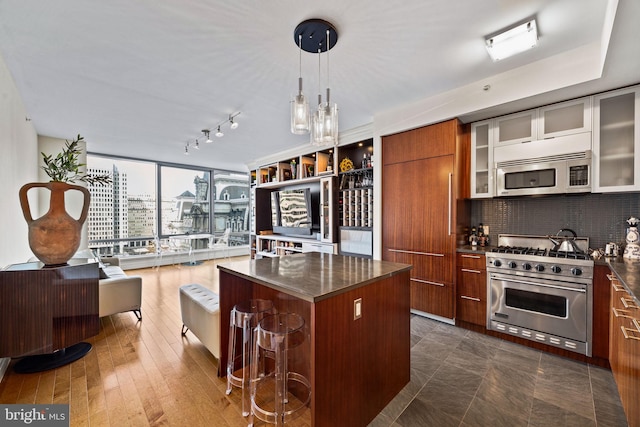 kitchen featuring appliances with stainless steel finishes, a breakfast bar, pendant lighting, tasteful backsplash, and a kitchen island with sink