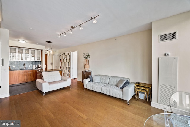 living room with an inviting chandelier, sink, and wood-type flooring