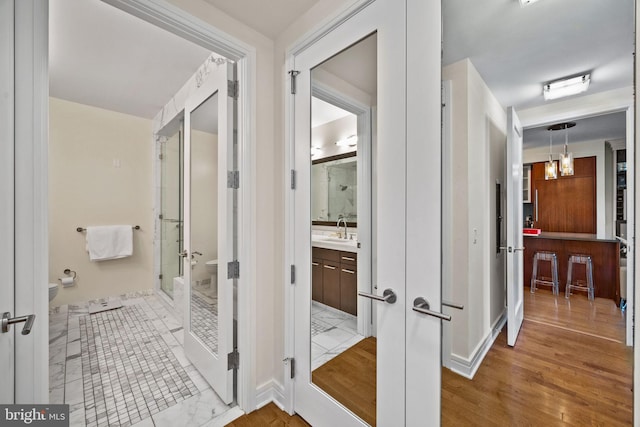 bathroom with hardwood / wood-style floors, an enclosed shower, vanity, french doors, and toilet