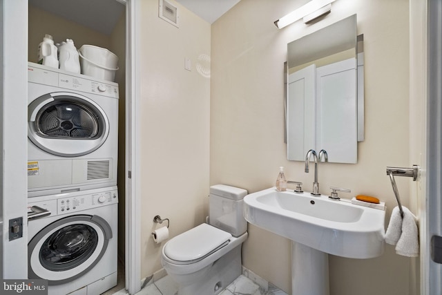 bathroom with stacked washing maching and dryer and toilet