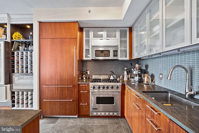 kitchen with appliances with stainless steel finishes, sink, dark stone countertops, and backsplash