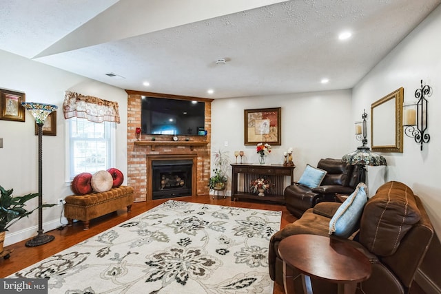 living room with a textured ceiling, a fireplace, baseboards, and wood finished floors