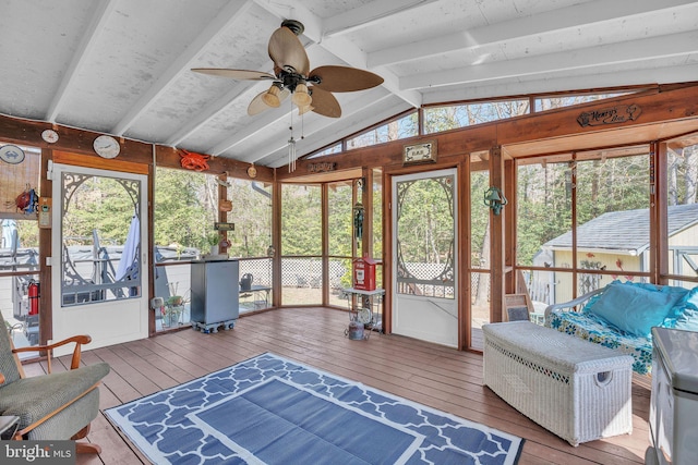 sunroom / solarium featuring lofted ceiling with beams, plenty of natural light, and a ceiling fan