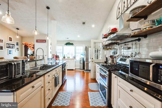 kitchen featuring stainless steel appliances, wood finished floors, a sink, visible vents, and tasteful backsplash