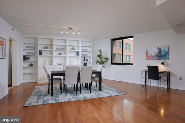 dining space with hardwood / wood-style flooring and a textured ceiling