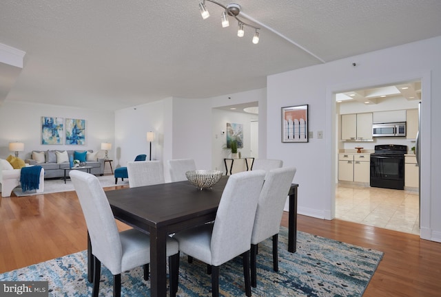 dining space with light hardwood / wood-style flooring and a textured ceiling