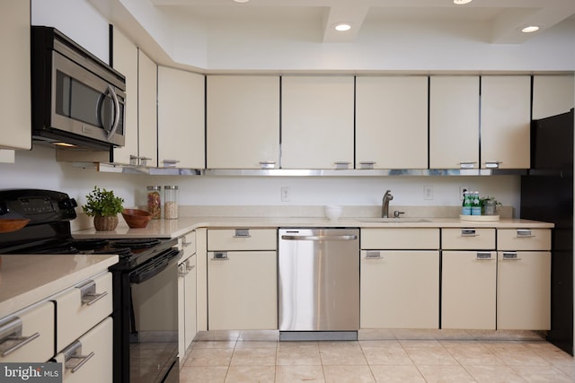 kitchen with sink, light tile patterned floors, white cabinets, and black appliances