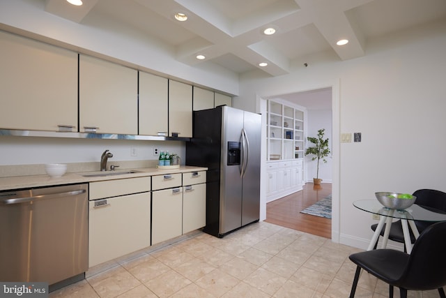 kitchen featuring sink, light tile patterned floors, stainless steel appliances, coffered ceiling, and beamed ceiling