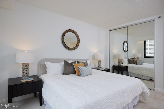 bedroom featuring a closet, light carpet, and a textured ceiling