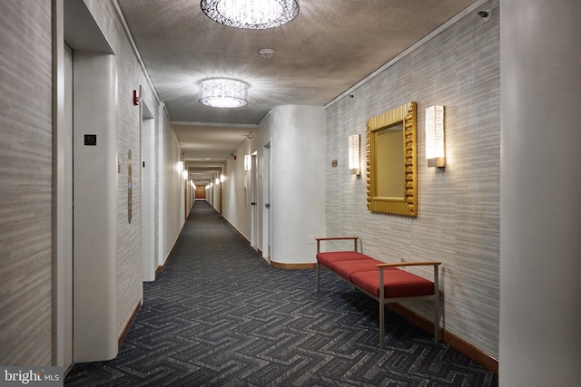 corridor featuring dark colored carpet, elevator, and a textured ceiling