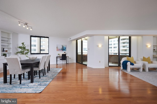 dining area with hardwood / wood-style floors, a textured ceiling, built in features, and a healthy amount of sunlight