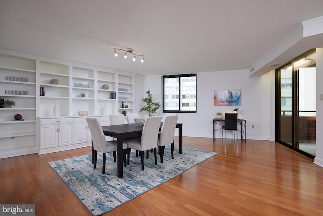 dining area featuring crown molding, hardwood / wood-style floors, and a textured ceiling