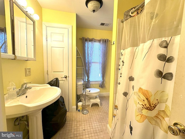 bathroom featuring curtained shower, tile patterned floors, and toilet