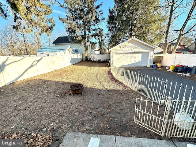 view of yard with a garage, an outdoor structure, and an outdoor fire pit