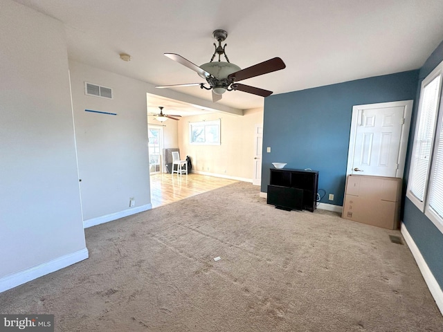 unfurnished living room featuring light carpet and ceiling fan