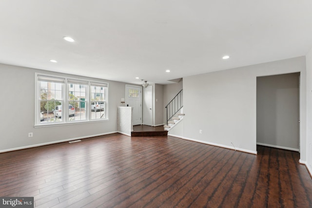 unfurnished living room with dark wood-style flooring, stairway, recessed lighting, and baseboards