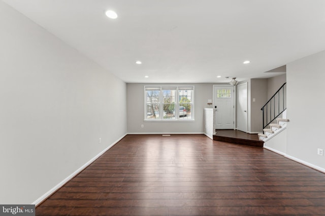 unfurnished living room with baseboards, stairway, dark wood-style flooring, and recessed lighting