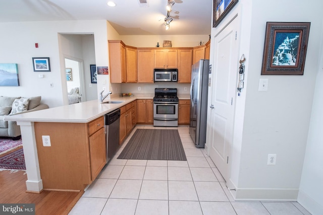 kitchen with sink, stainless steel appliances, a kitchen bar, light tile patterned flooring, and kitchen peninsula