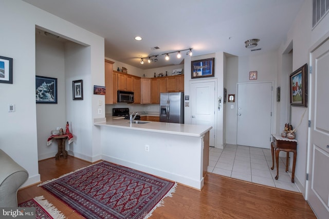 kitchen with sink, light tile patterned floors, stainless steel fridge, kitchen peninsula, and black range with electric cooktop