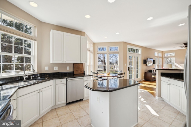 kitchen with a sink, plenty of natural light, white cabinets, and stainless steel dishwasher