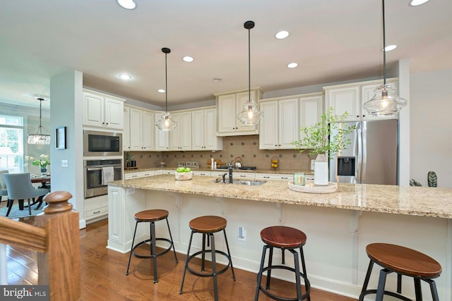 7916 Culloden Crest Ln, Gainesville, VA 20155 - kitchen with appliances with stainless steel finishes, decorative backsplash, a kitchen bar, pendant lighting, and light stone counters