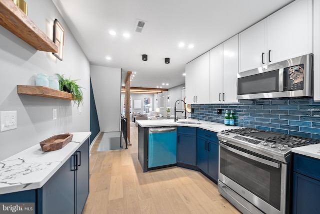 kitchen with blue cabinetry, appliances with stainless steel finishes, sink, and white cabinets