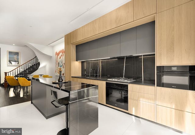 kitchen with black oven, a sink, and modern cabinets