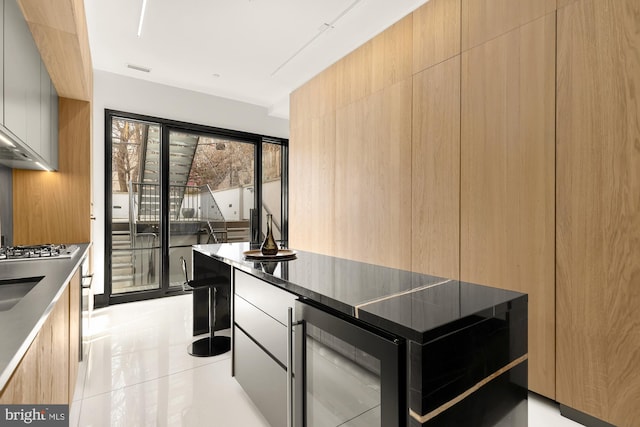 kitchen with beverage cooler, light tile patterned floors, modern cabinets, and stainless steel gas stovetop