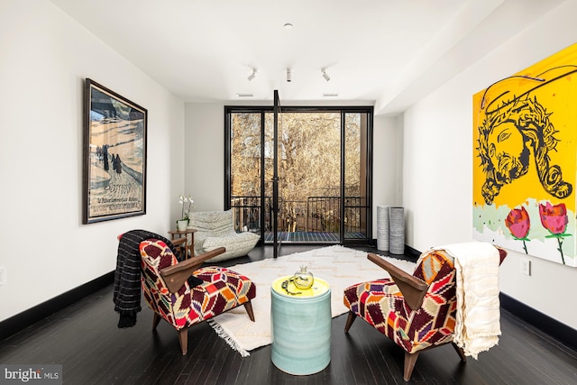 sitting room with a wall of windows, baseboards, and wood finished floors