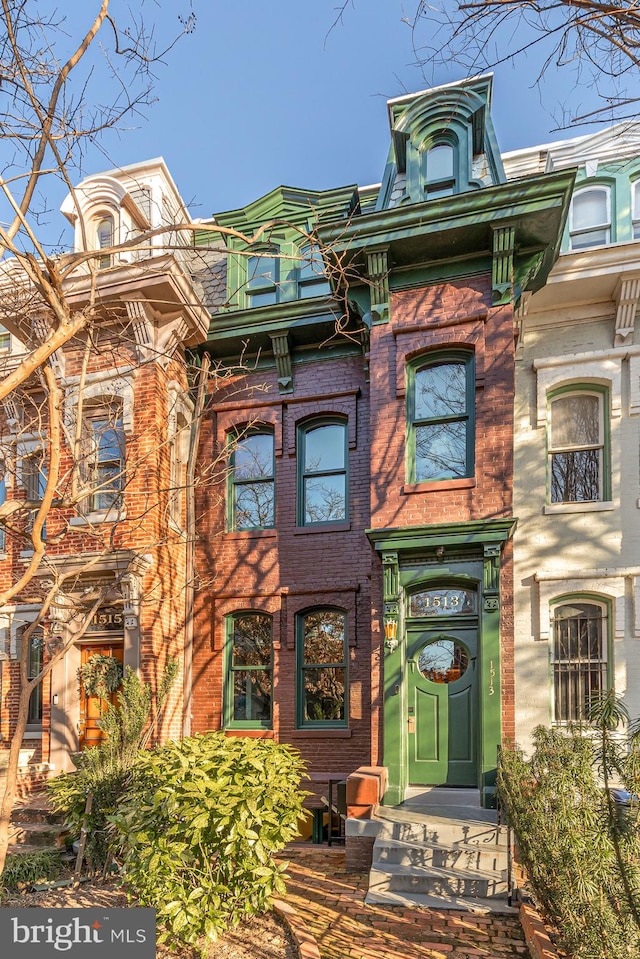 view of front of property featuring mansard roof and brick siding