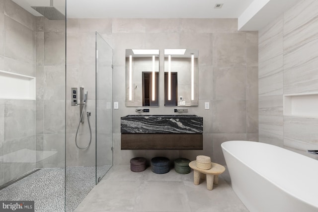 bathroom with a freestanding tub, tile walls, vanity, and a walk in shower