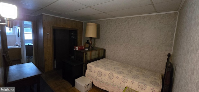 bedroom with crown molding, dark parquet floors, and a drop ceiling