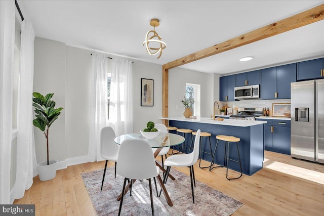 dining area with sink, beam ceiling, and light hardwood / wood-style flooring