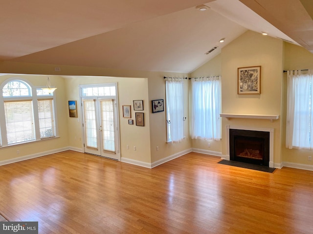 unfurnished living room featuring french doors, lofted ceiling, and light hardwood / wood-style floors