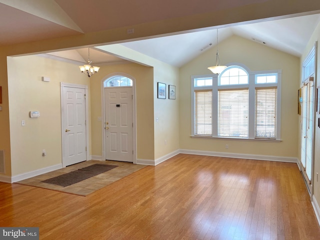 foyer entrance featuring lofted ceiling, an inviting chandelier, and light wood-type flooring